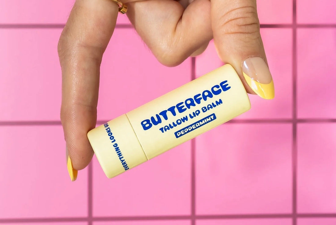 butterface tallow lip balm tube being held in fingers